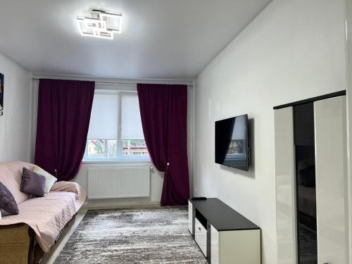 a bedroom with a bed and a window with purple curtains at New Apartment in Ivano-Frankivsʼk