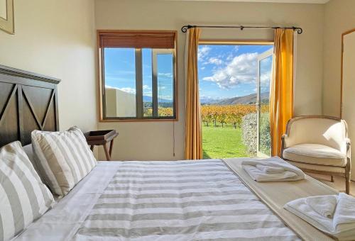 a bedroom with a bed and a window and a chair at Towan House at Carrick Winery in Cromwell