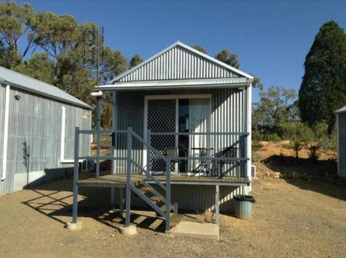 a small building with a porch and a dog sitting in front at Hill End Lodge in Hill End