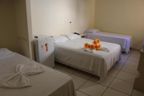 a hotel room with two beds and a refrigerator at Hotel Beira Rio in Aquidauana
