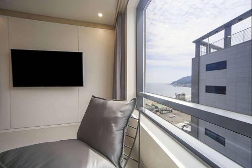 a room with a large window with a couch and a television at Hound Hotel Songjeong in Busan