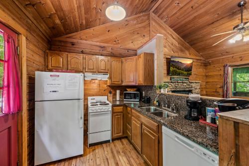 a kitchen with wooden cabinets and a white refrigerator at Romantic log cabin with hot tub in Pigeon Forge