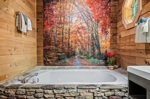 a bath tub in a bathroom with a painting of a forest at Romantic log cabin with hot tub in Pigeon Forge