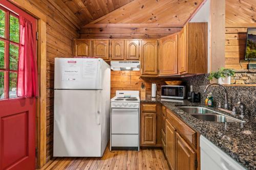 a kitchen with wooden cabinets and a white refrigerator at Romantic log cabin with hot tub in Pigeon Forge