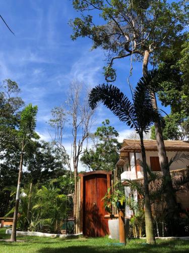 a house with a wooden gate and a tree at Villa Sagui Trancoso in Trancoso