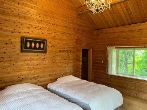 sypialnia z 2 łóżkami w drewnianym domku w obiekcie Kurokawa Marigold w mieście Minamioguni