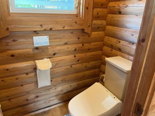 a small bathroom with a toilet and wooden walls at Kurokawa Marigold in Minamioguni
