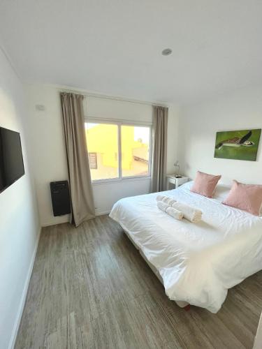a bedroom with a large white bed and a window at Atardeceres Chascomús in Chascomús