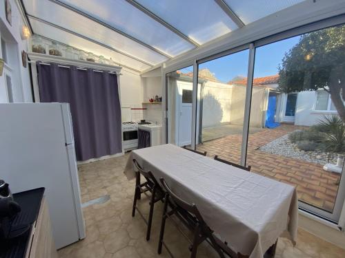 une chambre avec une table et une cuisine avec une grande fenêtre dans l'établissement Maison à Fouras, 3 chambres, cour ombragée, proche centre et plages - FR-1-709-67, à Fouras