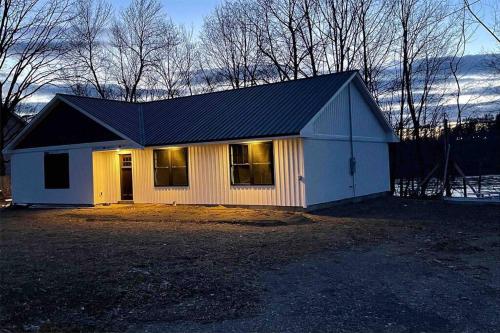 a small white house with a black roof at New ranch on RIVER with spectacular views in Brewer