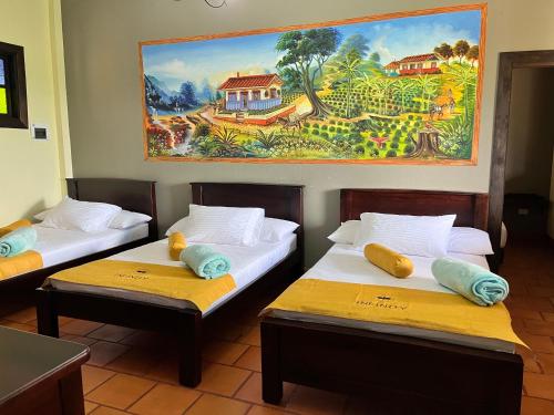 dwa łóżka w pokoju z obrazem na ścianie w obiekcie Hotel Campestre Los Mangos w mieście Quimbaya