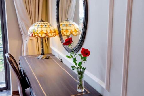 a table with two lamps and a vase with roses on it at Sophia Hotel in Hai Phong