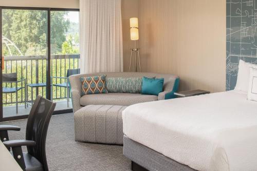 a hotel room with a bed and a couch and a balcony at Courtyard Seattle Sea-Tac Area in Tukwila
