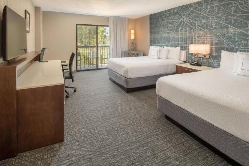 a hotel room with two beds and a flat screen tv at Courtyard Seattle Sea-Tac Area in Tukwila