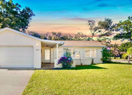 a white house with a garage in a yard at Easy BNB Close to Beaches, Billiard,Ping-Pong Table, Lanai, Fire Pit, BBQ, Patio, Back Yard in New Port Richey