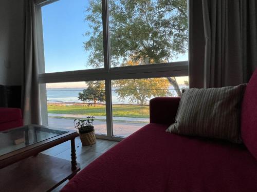 a living room with a red couch and a large window at Atardeceres Chascomús in Chascomús