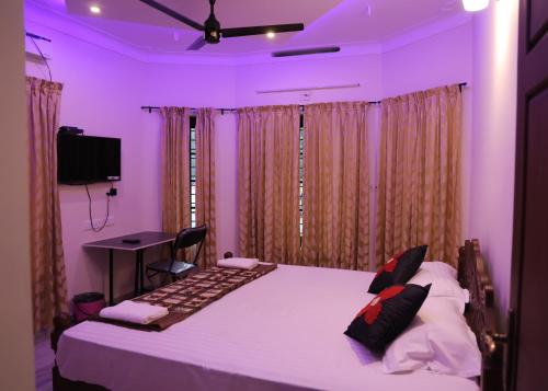 a bedroom with a large bed with purple lighting at Malpans Mansion Villa in Nedumbassery