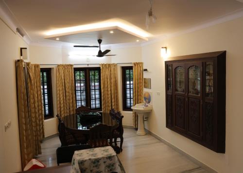 a living room with a table and chairs and windows at Malpans Mansion Villa in Nedumbassery