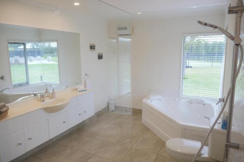 a bathroom with a tub and a toilet and a sink at Lodge On St Georges in Havelock North
