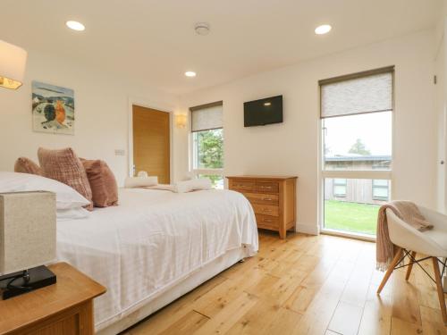 a white bedroom with two beds and a television at Elm in Truro