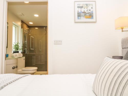 Un dormitorio con una cama blanca y un baño. en Elm, en Truro