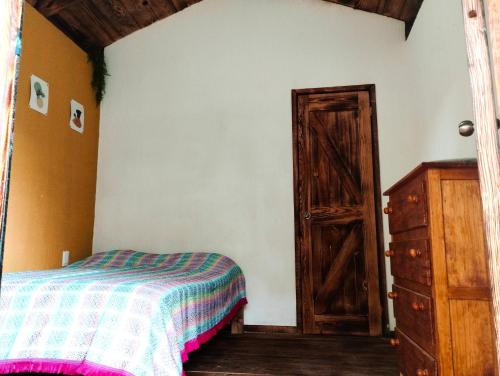1 dormitorio con 1 cama y puerta abierta en La cabaña de Aurora en Comala