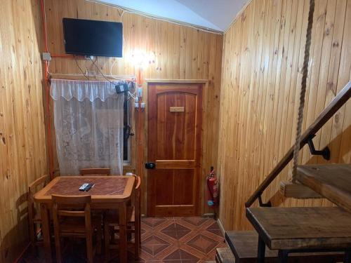 Habitación pequeña con mesa y TV en la pared. en Cabañas Armandiños, en Pichidangui
