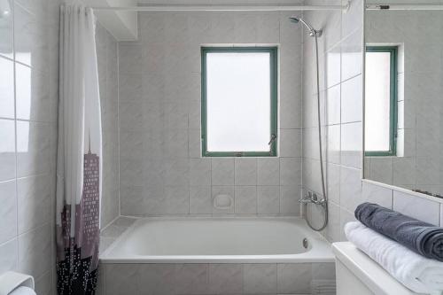 a white bathroom with a tub and a window at Primera línea, Viña del Mar-ByHospédate in Viña del Mar