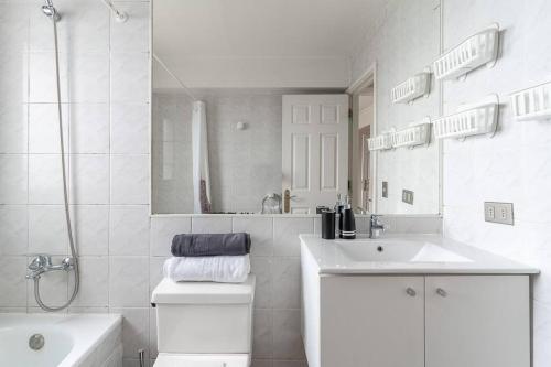 La salle de bains blanche est pourvue d'un lavabo, de toilettes et d'une baignoire. dans l'établissement primera linea viña del mar, à Viña del Mar