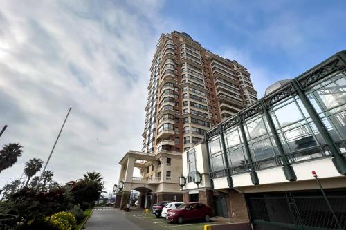 a large building with cars parked in front of it at Primera línea, Viña del Mar-ByHospédate in Viña del Mar