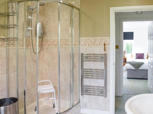 a glass shower in a bathroom with a stool at Meadow View in Hockering