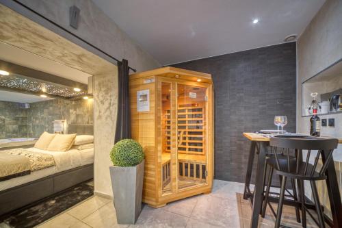 a bedroom with a bed and a bar with a table at L'Eden Love - Jacuzzi / Sauna in Grenoble