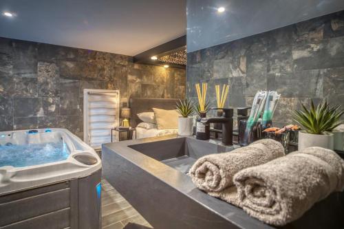 a bathroom with a tub and a sink with towels at L'Eden Love - Jacuzzi / Sauna in Grenoble