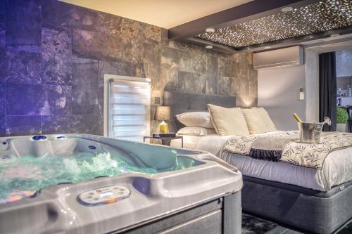 La salle de bains est pourvue d'une baignoire à côté d'un lit. dans l'établissement L'Eden Love - Jacuzzi / Sauna, à Grenoble