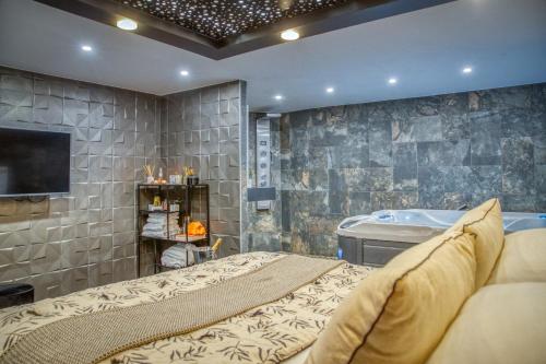 a bedroom with a tub and a bed and a television at L'Eden Love - Jacuzzi / Sauna in Grenoble