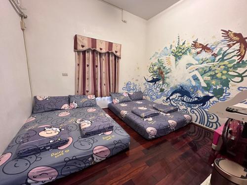 Duas camas e um sofá num quarto com um mural em Instructor 818 Rooms Homestay em Xiaoliuqiu