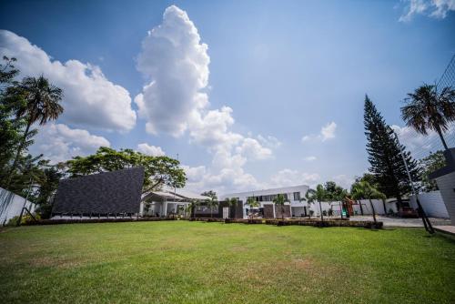 a large grassy yard with a building and palm trees at Hermosa habitación para pareja in Rozo