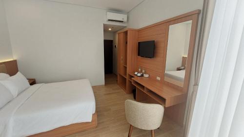 1 dormitorio con cama, escritorio y espejo en AYMAN SYARIAH HOTEL, en Surabaya