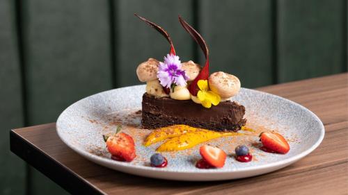 a piece of chocolate cake on a plate with fruit at Holiday Inn London Gatwick - Worth by IHG in Crawley