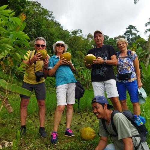 a group of people standing in the grass holding coconuts at Tastura Homestay in Praya