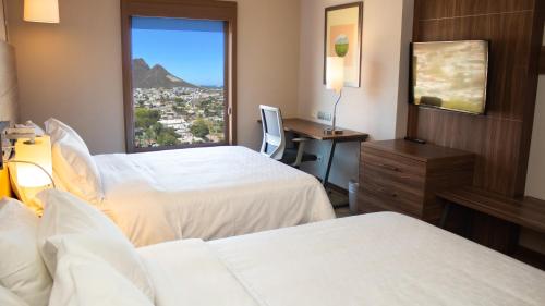 グアイマスにあるHoliday Inn Express Guaymas, an IHG Hotelのベッド2台、デスク、窓が備わるホテルルームです。