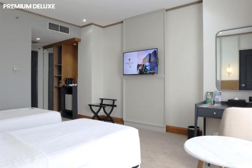 a bedroom with two beds and a tv on the wall at Hotel Dafam Semarang in Semarang