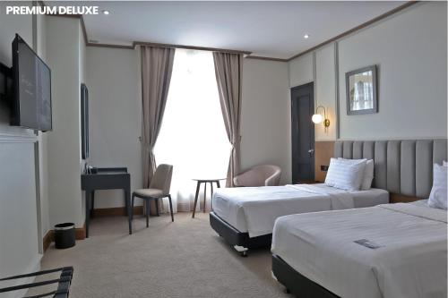 a hotel room with two beds and a desk at Hotel Dafam Semarang in Semarang
