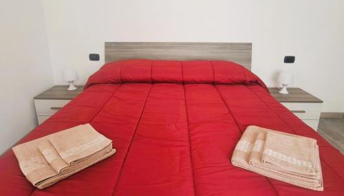 ein rotes Bett mit zwei Handtüchern darüber in der Unterkunft LA PETITE MAISON in Agrate Brianza