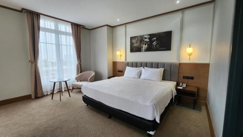 une chambre d'hôtel avec un lit et une chaise dans l'établissement Hotel Dafam Semarang, à Semarang