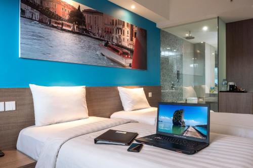 a laptop computer sitting on top of a bed at The Hills Batam in Nagoya