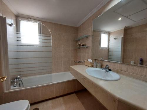ein Badezimmer mit einem Waschbecken, einer Badewanne und einem Spiegel in der Unterkunft La Palmera - Amazing apartment with excellent location & views in Marbella