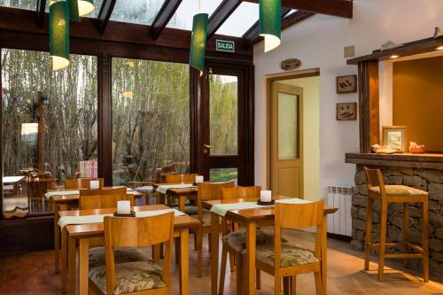 a restaurant with wooden tables and chairs and windows at Hosteria Roblesur in El Calafate