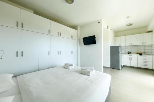a white bedroom with a bed and a refrigerator at דירות גני תערוכה - TLV university apartments near Expo by Sea N' Rent in Tel Aviv