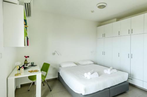 a white bedroom with a bed and a desk at דירות גני תערוכה - TLV university apartments near Expo by Sea N' Rent in Tel Aviv